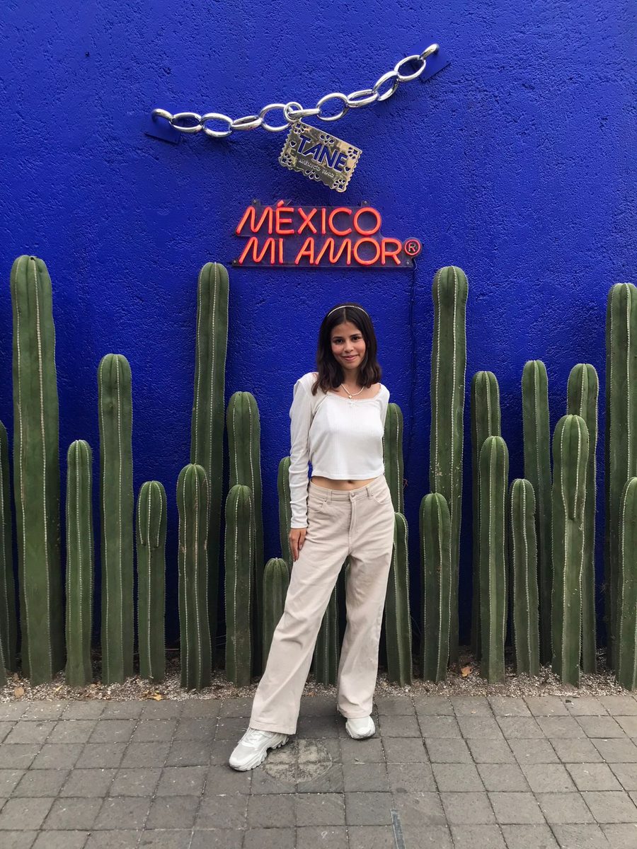 Sofía ante un muro azul con cactus y un letrero de neón que dice México mi amor